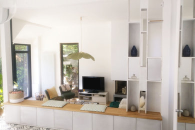 Modern inredning av ett stort allrum med öppen planlösning, med ett finrum, vita väggar, klinkergolv i keramik, en dubbelsidig öppen spis, en spiselkrans i gips, en fristående TV och blått golv