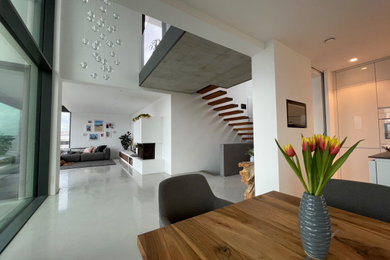 Repräsentatives, Offenes Modernes Wohnzimmer mit weißer Wandfarbe, Betonboden, Kamin, verputzter Kaminumrandung und grauem Boden in Stuttgart