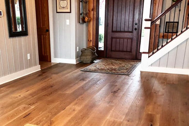 Example of a large mountain style light wood floor entryway design in New York with gray walls and a dark wood front door