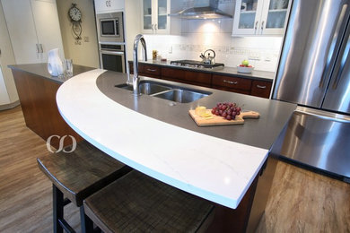 Mid-sized elegant galley vinyl floor open concept kitchen photo in Other with an undermount sink, flat-panel cabinets, dark wood cabinets, quartz countertops, white backsplash, ceramic backsplash, stainless steel appliances and an island