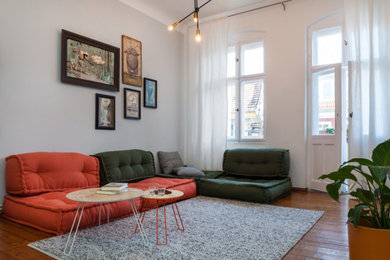 Mittelgroßes Eklektisches Wohnzimmer ohne Kamin mit grauer Wandfarbe, dunklem Holzboden und freistehendem TV in Berlin