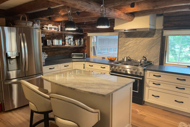 Example of a mid-sized u-shaped light wood floor, beige floor and wood ceiling kitchen design in Boston with an undermount sink, shaker cabinets, white cabinets, granite countertops, stainless steel appliances, an island and black countertops