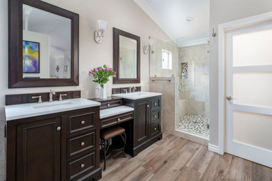 Example of a large classic master beige tile and porcelain tile vinyl floor, brown floor, double-sink and vaulted ceiling bathroom design in Los Angeles with beaded inset cabinets, brown cabinets, a two-piece toilet, beige walls, an undermount sink, quartz countertops, a hinged shower door, white countertops, a niche and a freestanding vanity