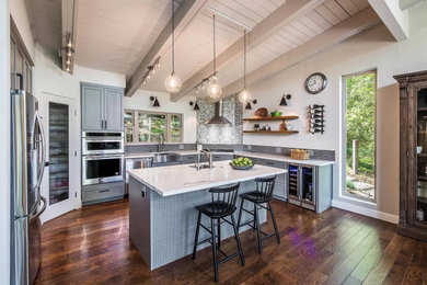 Inspiration for a large country u-shaped exposed beam open concept kitchen remodel in San Francisco with a farmhouse sink, shaker cabinets, gray cabinets, quartz countertops, gray backsplash, ceramic backsplash, stainless steel appliances, an island and white countertops