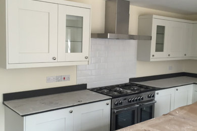 This is an example of a medium sized modern kitchen in Cambridgeshire with shaker cabinets, quartz worktops, stainless steel appliances and an island.