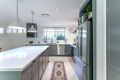 Inspiration for a mid-sized traditional l-shaped open plan kitchen in Sydney with an integrated sink, shaker cabinets, grey cabinets, quartz benchtops, white splashback, subway tile splashback, black appliances, with island, white floor and white benchtop.