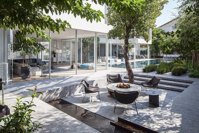 This is an example of an expansive contemporary back patio in London with no cover, a fire feature and tiled flooring.