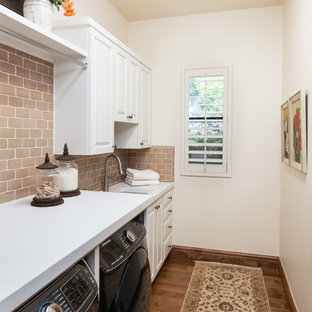 Medium sized mediterranean galley separated utility room in Phoenix with a submerged sink, raised-panel cabinets, white cabinets, concrete worktops, white walls, medium hardwood flooring, a side by side washer and dryer, brown floors and white worktops.