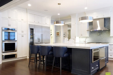 Large transitional u-shaped dark wood floor and brown floor kitchen photo in New York with an undermount sink, recessed-panel cabinets, white cabinets, marble countertops, gray backsplash, mosaic tile backsplash, stainless steel appliances, an island and white countertops