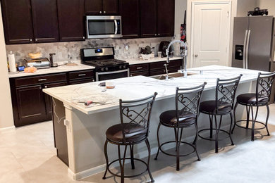Inspiration for a large l-shaped ceramic tile and beige floor open concept kitchen remodel in Houston with a farmhouse sink, dark wood cabinets, granite countertops, gray backsplash, ceramic backsplash, stainless steel appliances, an island and white countertops