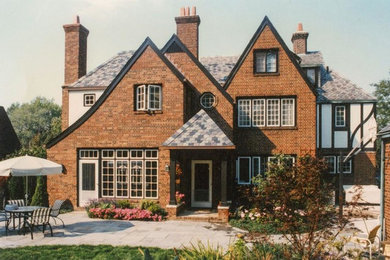 Example of a large classic brown three-story brick house exterior design in Cleveland with a hip roof and a tile roof