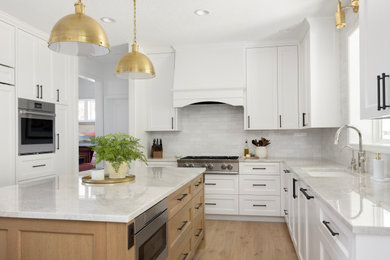 Example of a large classic light wood floor eat-in kitchen design in Portland with a single-bowl sink, shaker cabinets, white cabinets, quartzite countertops, white backsplash, subway tile backsplash, stainless steel appliances, an island and beige countertops