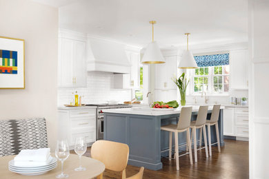 Example of a transitional medium tone wood floor and brown floor eat-in kitchen design in St Louis with shaker cabinets, white cabinets, white backsplash, subway tile backsplash, stainless steel appliances, an island and gray countertops