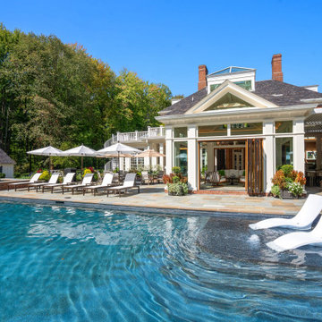 Poolside view of the open NanaWall cabana with loungers, dining and outdoor fire