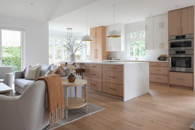 Inspiration for a mid-sized contemporary galley light wood floor open concept kitchen remodel in Vancouver with an undermount sink, shaker cabinets, light wood cabinets, quartz countertops, white backsplash, quartz backsplash, stainless steel appliances, an island and white countertops