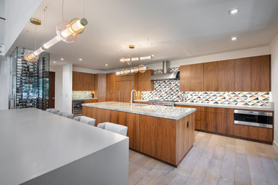 Inspiration for a large modern single-wall light wood floor and brown floor open concept kitchen remodel in Other with an undermount sink, flat-panel cabinets, medium tone wood cabinets, granite countertops, multicolored backsplash, mosaic tile backsplash, stainless steel appliances, two islands and gray countertops