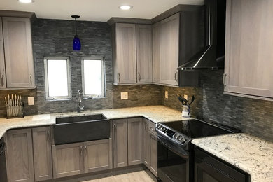 Photo of a tropical kitchen in Tampa with a farmhouse sink, shaker cabinets, grey cabinets, granite benchtops, grey splashback, stone tile splashback and grey floor.