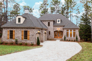 Example of a large transitional brown two-story brick house exterior design in Atlanta with a hip roof and a shingle roof