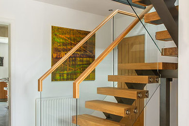 Design ideas for a medium sized contemporary wood u-shaped glass railing staircase in West Midlands with open risers.