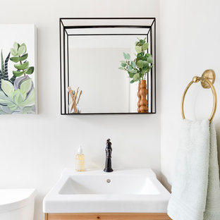 Immagine di una piccola stanza da bagno minimalista con ante in legno chiaro, vasca ad alcova, vasca/doccia, WC a due pezzi, pareti beige, pavimento in marmo, lavabo integrato, pavimento nero e doccia con tenda