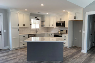 Inspiration for a mid-sized craftsman l-shaped vinyl floor, gray floor and vaulted ceiling open concept kitchen remodel in Atlanta with a farmhouse sink, shaker cabinets, white cabinets, quartz countertops, white backsplash, ceramic backsplash, stainless steel appliances, an island and white countertops