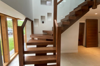 Exemple d'un escalier flottant tendance de taille moyenne avec des marches en bois, des contremarches en bois, un garde-corps en verre et éclairage.