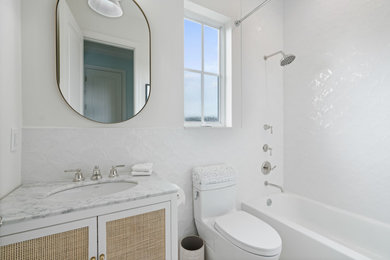 Diseño de cuarto de baño marinero con combinación de ducha y bañera, paredes blancas y lavabo bajoencimera