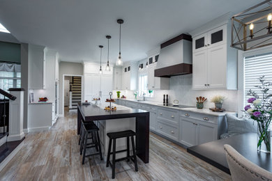 Large farmhouse l-shaped porcelain tile and brown floor enclosed kitchen photo in Other with an undermount sink, shaker cabinets, white cabinets, quartzite countertops, white backsplash, marble backsplash, paneled appliances, an island and white countertops