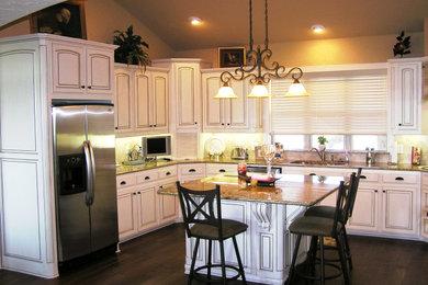 Eat-in kitchen photo in Dallas with raised-panel cabinets, distressed cabinets, stainless steel appliances and an island