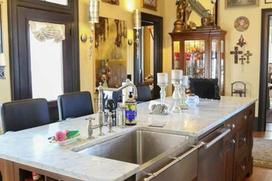 Elegant medium tone wood floor kitchen photo in Chicago with a farmhouse sink, raised-panel cabinets, dark wood cabinets, granite countertops, stainless steel appliances and an island