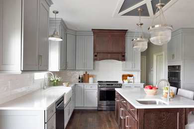 Eat-in kitchen - large transitional l-shaped medium tone wood floor, brown floor and wood ceiling eat-in kitchen idea in Philadelphia with a farmhouse sink, recessed-panel cabinets, gray cabinets, quartzite countertops, white backsplash, subway tile backsplash, stainless steel appliances, an island and white countertops
