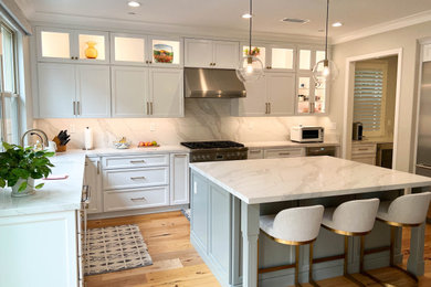 Example of a large transitional light wood floor and brown floor kitchen design in Orange County with an undermount sink, shaker cabinets, white cabinets, quartz countertops, white backsplash, quartz backsplash, stainless steel appliances, an island and white countertops