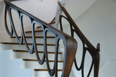 Foto de escalera en U con escalones de madera, contrahuellas de madera pintada y barandilla de madera