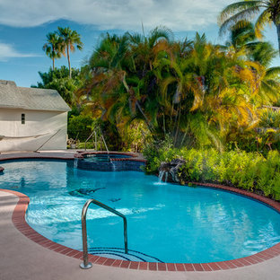 Diseño de piscinas y jacuzzis naturales, actuales, grandes, tipo riñón, en patio trasero, con suelo de hormigón estampado