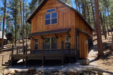 Example of a mountain style two-story wood and board and batten exterior home design in Other with a metal roof and a brown roof