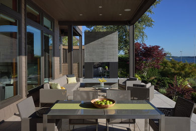 Photo of a mid-sized contemporary backyard patio in Seattle with natural stone pavers and a roof extension.