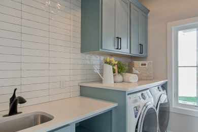 Example of a country ceramic tile laundry room design in Other with an undermount sink, recessed-panel cabinets, blue cabinets, quartz countertops, white backsplash, subway tile backsplash, a side-by-side washer/dryer and white countertops