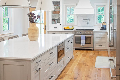 Inspiration for a large cottage l-shaped light wood floor and brown floor eat-in kitchen remodel in Other with a farmhouse sink, shaker cabinets, gray cabinets, white backsplash, subway tile backsplash, stainless steel appliances, an island and white countertops