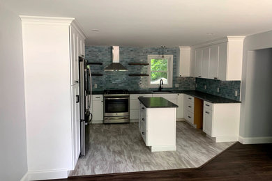 Eat-in kitchen - contemporary l-shaped eat-in kitchen idea in Boston with an undermount sink, shaker cabinets, white cabinets, granite countertops, blue backsplash, subway tile backsplash, stainless steel appliances, an island and black countertops