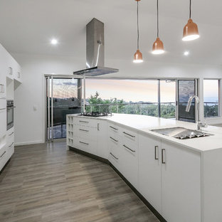 Cette photo montre une arrière-cuisine parallèle tendance de taille moyenne avec un évier encastré, un placard avec porte à panneau encastré, des portes de placard blanches, un plan de travail en quartz modifié, une crédence orange, une crédence en feuille de verre, un sol en carrelage de céramique et un îlot central.