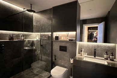 Large contemporary grey and black ensuite wet room bathroom in London with flat-panel cabinets, grey cabinets, multi-coloured tiles, porcelain tiles, quartz worktops, multi-coloured worktops, a single sink, a wall mounted toilet, multi-coloured walls, porcelain flooring, an integrated sink, black floors, an open shower, a wall niche and a built in vanity unit.