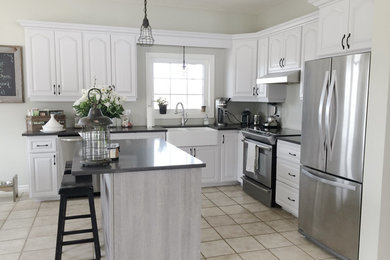 Large transitional l-shaped porcelain tile open concept kitchen photo in Toronto with a farmhouse sink, white cabinets, gray backsplash, stainless steel appliances, an island, raised-panel cabinets and quartz countertops