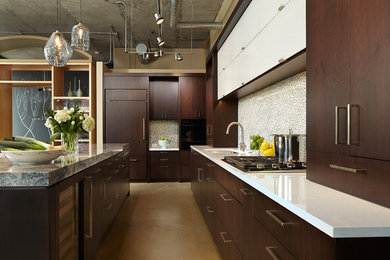Mid-sized modern l-shaped open plan kitchen in Minneapolis with an undermount sink, flat-panel cabinets, dark wood cabinets, granite benchtops, white splashback, glass tile splashback, panelled appliances, concrete floors and with island.