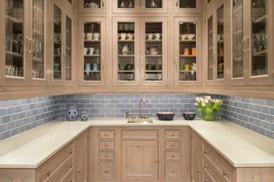 This is an example of a small traditional u-shaped kitchen pantry in Houston with glass-front cabinets, light wood cabinets, blue splashback, medium hardwood floors, no island, marble benchtops and ceramic splashback.