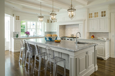 Transitional medium tone wood floor kitchen photo in Boston with an undermount sink, raised-panel cabinets, white cabinets, gray backsplash, stainless steel appliances and an island