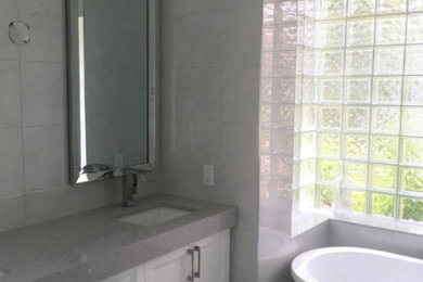 Freestanding bathtub - mid-sized modern master white tile and marble tile marble floor and gray floor freestanding bathtub idea in Other with recessed-panel cabinets, white cabinets, gray walls, an undermount sink, marble countertops and gray countertops