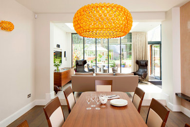 This is an example of a medium sized contemporary open plan dining room in Cambridgeshire with beige walls, dark hardwood flooring and brown floors.