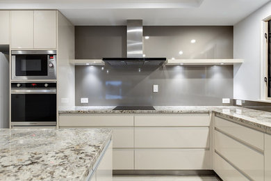 Inspiration for a mid-sized modern l-shaped eat-in kitchen in Sunshine Coast with flat-panel cabinets, white cabinets, quartz benchtops, grey splashback, concrete floors, with island and white benchtop.