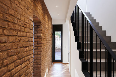 Design ideas for a mid-sized industrial hallway in Frankfurt with white walls, medium hardwood floors and brown floor.