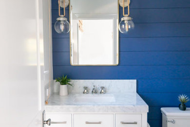 Cette image montre une petite salle de bain marine avec des portes de placard blanches, un mur bleu, un plan de toilette en marbre, meuble simple vasque, un plafond en lambris de bois et du lambris de bois.